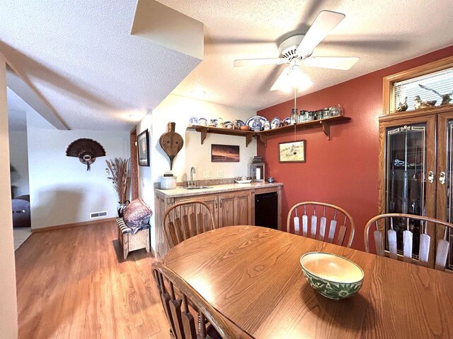 12541 Fleetwood Rd, Tomah, WI 54660 - dining space featuring a textured ceiling, light wood-style flooring, wet bar, and a ceiling fan