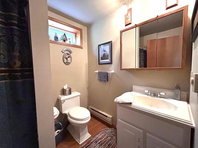 12541 Fleetwood Rd, Tomah, WI 54660 - bathroom with a baseboard heating unit, wood finished floors, toilet, vanity, and a shower with shower curtain