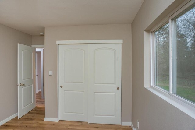 N3725 County Road Ee, Redgranite, WI 54970 - unfurnished bedroom with multiple windows, light wood-style flooring, baseboards, and a closet