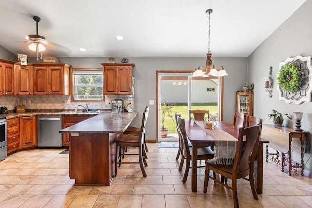 2891 Yellow Jasmine Way, Green Bay, WI 54313 - kitchen featuring appliances with stainless steel finishes, brown cabinets, a chandelier, decorative backsplash, and a breakfast bar