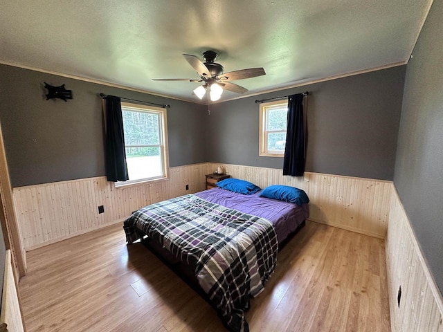 6111 Magnolia Dr, Wisconsin Rapids, WI 54494 - bedroom featuring a wainscoted wall, wood walls, multiple windows, wood finished floors, and crown molding
