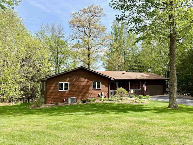 7002 Wildwood Ln, Rhinelander, WI 54501 - view of side of home with a yard, central AC unit, a garage, and driveway
