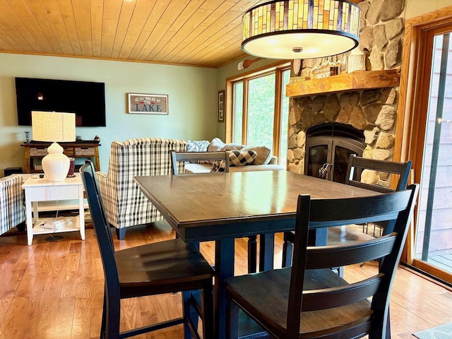 7002 Wildwood Ln, Rhinelander, WI 54501 - dining area featuring crown molding, a fireplace, healthy amount of natural light, and wood finished floors