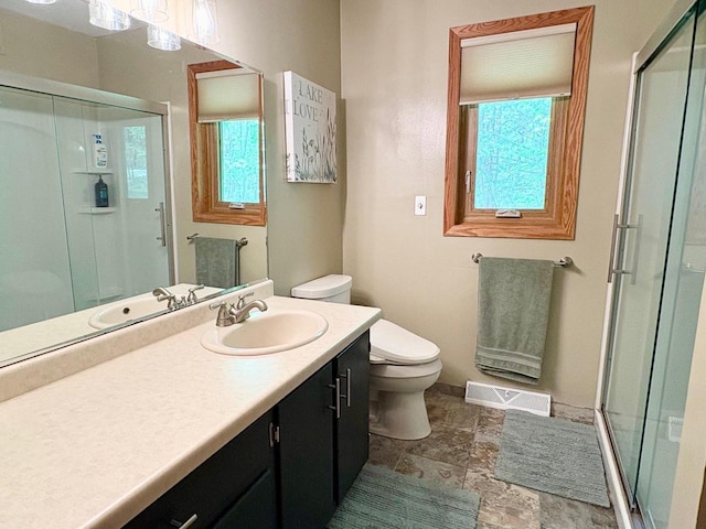 7002 Wildwood Ln, Rhinelander, WI 54501 - full bathroom with a stall shower, toilet, vanity, and stone finish floors