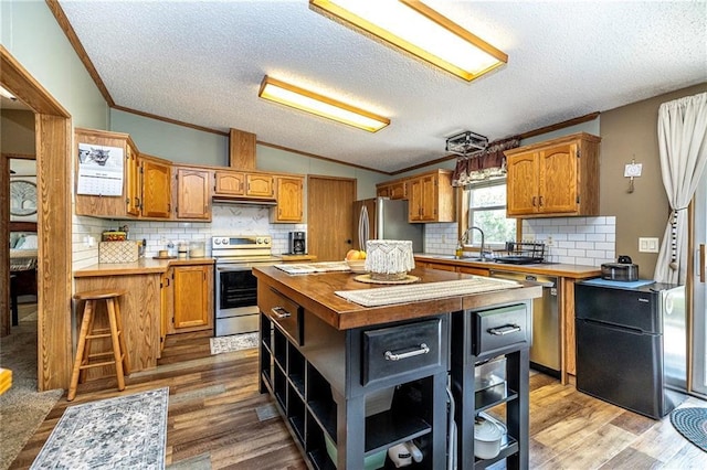 W14312 Montgomery Rd, Hixton, WI 54635 - kitchen featuring appliances with stainless steel finishes, open shelves, ornamental molding, a textured ceiling, and backsplash