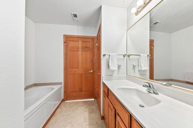 2142 Chateau Ct Unit 308-2, Grafton, WI 53024 - bathroom featuring a bath, vanity, and a textured ceiling