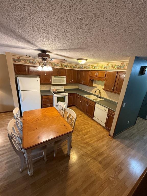 51 Stump Lake Rd, Chippewa Falls, WI 54729 - kitchen featuring white appliances, a sink, a textured ceiling, light wood-type flooring, and dark countertops
