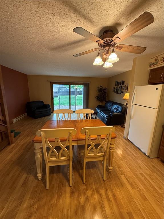 51 Stump Lake Rd, Chippewa Falls, WI 54729 - dining space featuring a baseboard radiator, a textured ceiling, light wood-style floors, and a ceiling fan