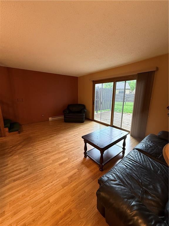 51 Stump Lake Rd, Chippewa Falls, WI 54729 - living area featuring a baseboard heating unit, light wood-style floors, and a textured ceiling