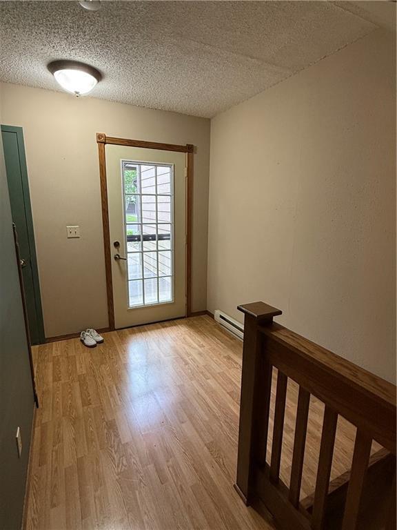 51 Stump Lake Rd, Chippewa Falls, WI 54729 - doorway featuring light wood-style flooring, a baseboard radiator, a textured ceiling, and baseboards
