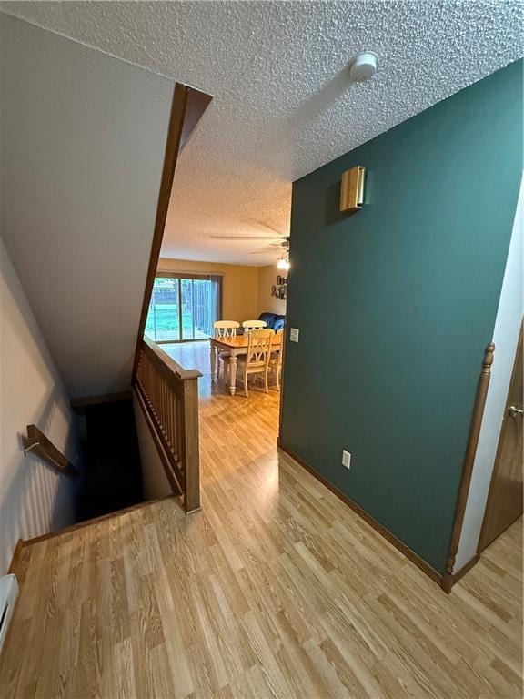 51 Stump Lake Rd, Chippewa Falls, WI 54729 - corridor featuring an upstairs landing, a textured ceiling, light wood-style floors, and baseboard heating
