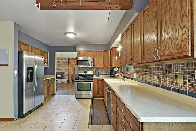 N7094 Evergreen Ln, Elkhorn, WI 53121 - kitchen with stainless steel appliances, a sink, brown cabinetry, tasteful backsplash, and light countertops