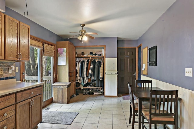 N7094 Evergreen Ln, Elkhorn, WI 53121 - kitchen featuring a ceiling fan, brown cabinets, light tile patterned floors, light countertops, and wainscoting