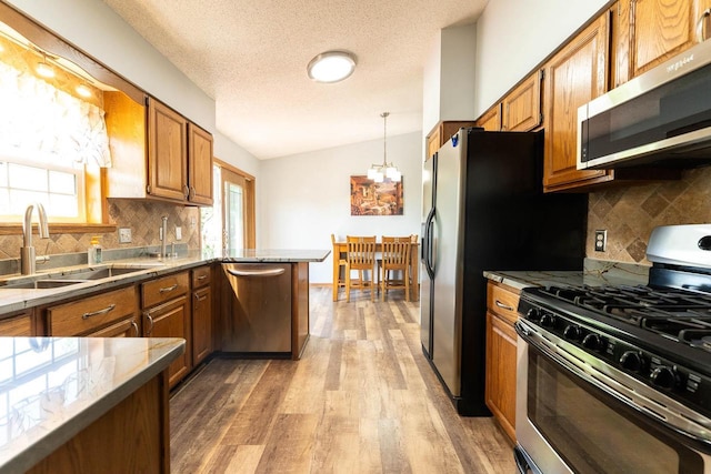 715 Farmer Ave, Tomah, WI 54660 - kitchen featuring appliances with stainless steel finishes, a sink, light wood finished floors, brown cabinetry, and backsplash