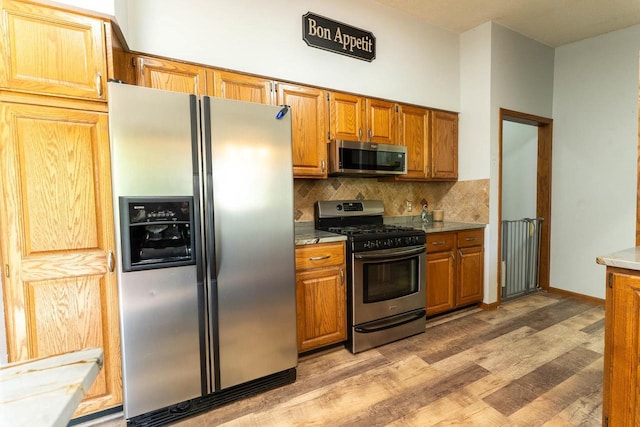 715 Farmer Ave, Tomah, WI 54660 - kitchen with stainless steel appliances, light wood finished floors, decorative backsplash, and brown cabinets