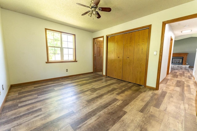 715 Farmer Ave, Tomah, WI 54660 - unfurnished bedroom with wood finished floors, baseboards, a closet, a textured ceiling, and a fireplace with raised hearth