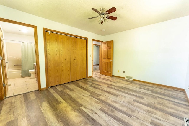 715 Farmer Ave, Tomah, WI 54660 - unfurnished bedroom featuring wood finished floors, a closet, ensuite bathroom, baseboards, and a ceiling fan
