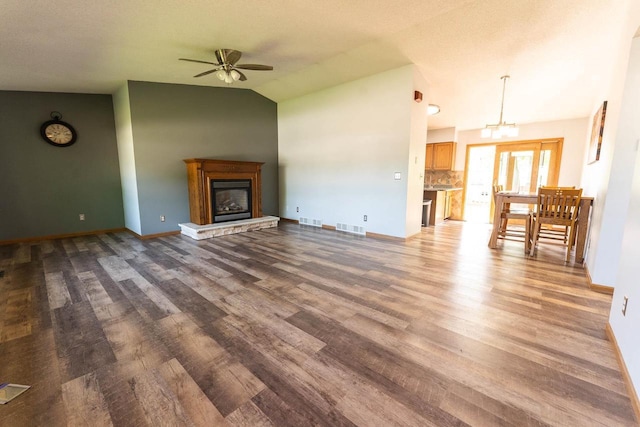 715 Farmer Ave, Tomah, WI 54660 - unfurnished living room featuring vaulted ceiling, a ceiling fan, wood finished floors, baseboards, and a glass covered fireplace