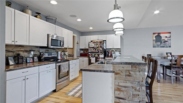 3312 White Oak Ln, Eau Claire, WI 54703 - kitchen featuring stainless steel appliances, light wood-type flooring, dark countertops, a sink, and backsplash