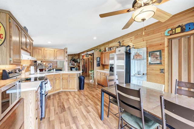 W6576 20th Dr, Wautoma, WI 54982 - kitchen with under cabinet range hood, appliances with stainless steel finishes, light countertops, ceiling fan, and wooden walls