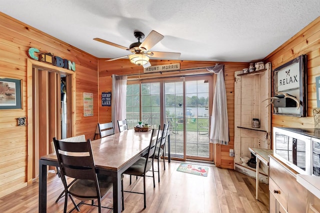 W6576 20th Dr, Wautoma, WI 54982 - dining space featuring wooden walls, light wood finished floors, a ceiling fan, and a textured ceiling