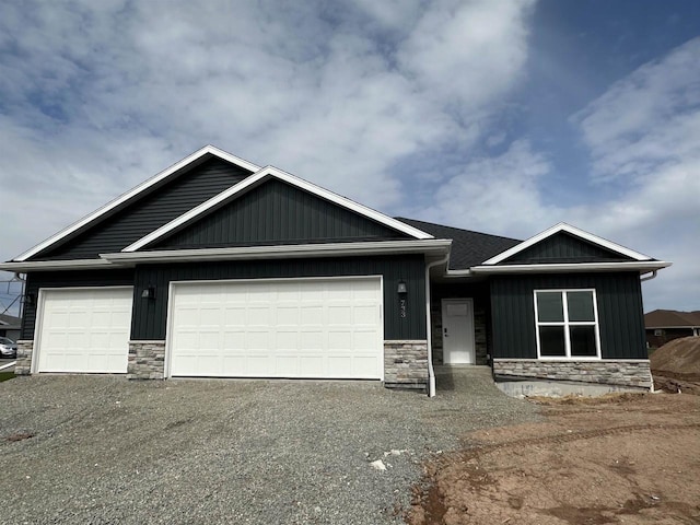 733 Tambour Ct, De Pere, WI 54115 - view of front of property with stone siding, an attached garage, asphalt driveway, and board and batten siding