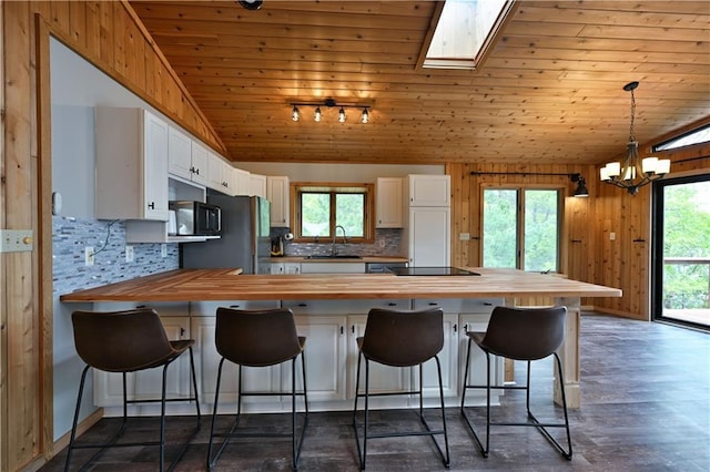 W7607 Whitetail Dr, Minong, WI 54859 - kitchen featuring wooden counters, vaulted ceiling, black appliances, healthy amount of natural light, and decorative backsplash