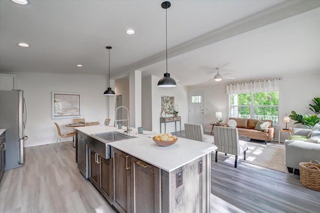 103 Lake Ct, Edgerton, WI 53534 - kitchen with stainless steel appliances, a sink, light wood-type flooring, dark brown cabinets, and open floor plan