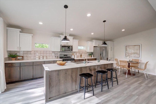 103 Lake Ct, Edgerton, WI 53534 - kitchen with appliances with stainless steel finishes, decorative backsplash, an island with sink, light countertops, and light wood-style flooring