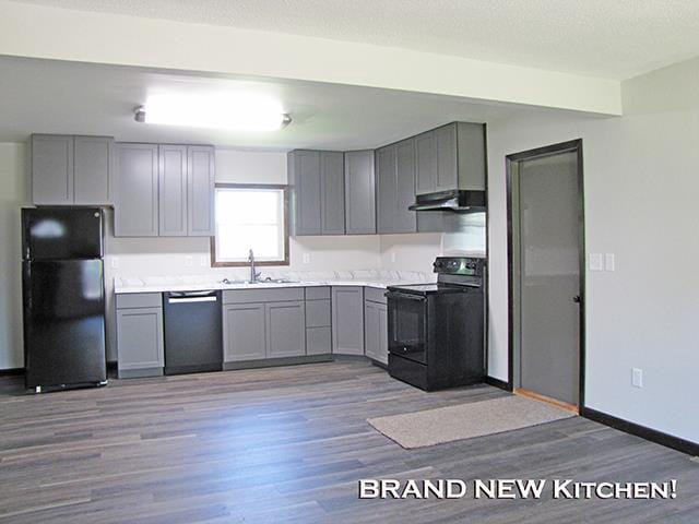 79 1st Ave, Benton, WI 53803 - kitchen with black appliances, gray cabinetry, under cabinet range hood, wood finished floors, and a textured ceiling