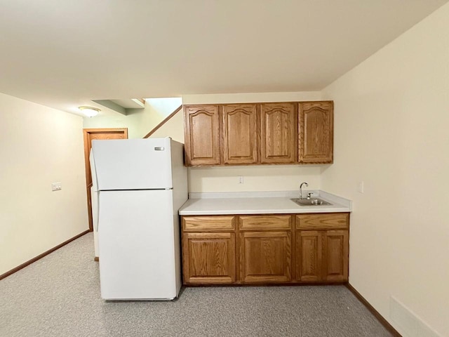 407 Overlook Ter, Marshall, WI 53559 - kitchen with freestanding refrigerator, a sink, brown cabinets, light countertops, and light carpet