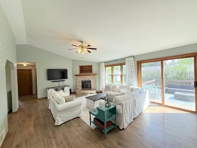 407 Overlook Ter, Marshall, WI 53559 - living room featuring vaulted ceiling, a fireplace, a ceiling fan, wood finished floors, and arched walkways