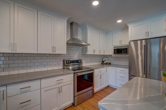 2330 Mica Rd, Madison, WI 53719 - kitchen with stainless steel appliances, wall chimney range hood, white cabinetry, light wood-style floors, and recessed lighting