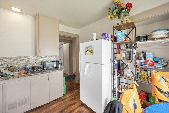 1515 Harrison St, Oshkosh, WI 54901 - kitchen with freestanding refrigerator, dark wood-style floors, decorative backsplash, white cabinets, and black microwave