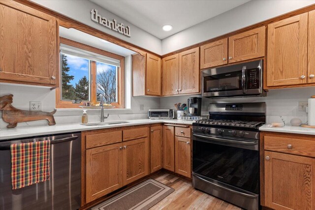 1502 Ridgewood Dr Unit D-7, West Bend, WI 53095 - kitchen with stainless steel appliances, a sink, light wood-style floors, light countertops, and brown cabinetry
