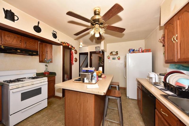 kitchen featuring white appliances, under cabinet range hood, a kitchen island, a kitchen bar, and a ceiling fan