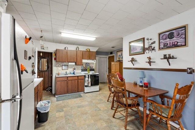 4084 Eagle Mound Pass, Deforest, WI 53532 - kitchen with white appliances, brown cabinetry, light countertops, tasteful backsplash, and a sink