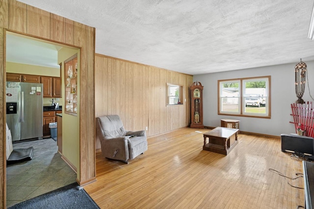 538 124th St, Franksville, WI 53126 - living room with wood walls, light wood-style flooring, a textured ceiling, and baseboards