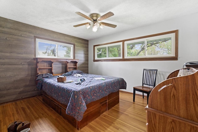 538 124th St, Franksville, WI 53126 - bedroom featuring wooden walls, wood finished floors, a ceiling fan, and a textured ceiling