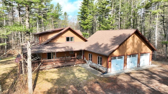 7496 River Rd, Lake Tomahawk, WI 54558 - rustic home with roof with shingles, covered porch, driveway, and a garage
