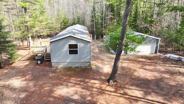 7496 River Rd, Lake Tomahawk, WI 54558 - view of side of property featuring an outbuilding, a forest view, a deck, a detached garage, and stairs