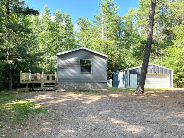 7496 River Rd, Lake Tomahawk, WI 54558 - view of side of home featuring a garage, a wooden deck, an outbuilding, and dirt driveway