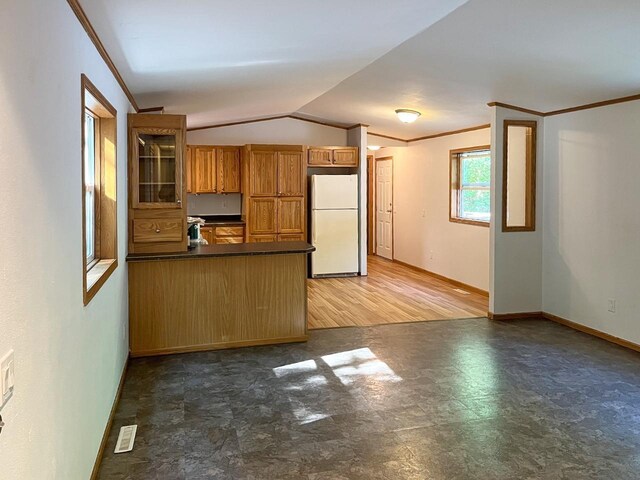 7496 River Rd, Lake Tomahawk, WI 54558 - kitchen with freestanding refrigerator, dark countertops, a peninsula, brown cabinetry, and vaulted ceiling