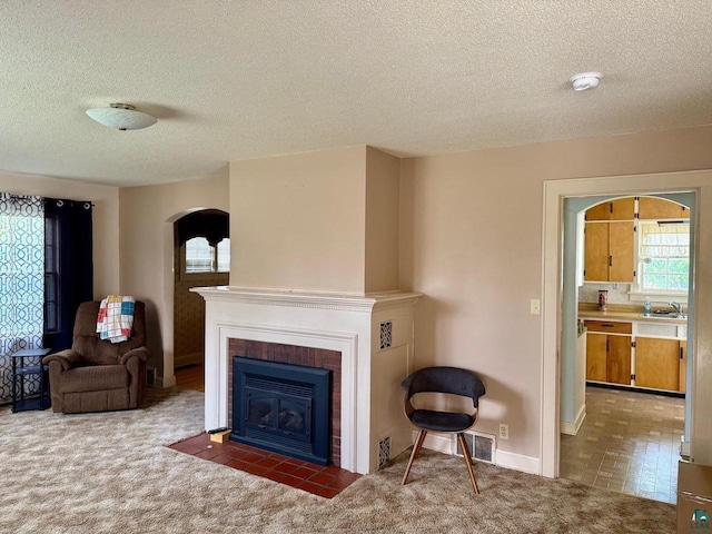 514 W 9th Ave, Ashland, WI 54806 - living room featuring a textured ceiling, arched walkways, a fireplace with flush hearth, carpet floors, and baseboards
