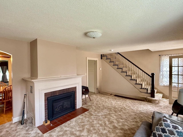 514 W 9th Ave, Ashland, WI 54806 - carpeted living room featuring stairs, a fireplace with flush hearth, a textured ceiling, and baseboards