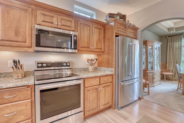 1826 Stonebridge Rd, Waukesha, WI 53188 - kitchen featuring appliances with stainless steel finishes, arched walkways, plenty of natural light, and light wood-style flooring