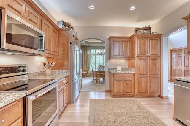 1826 Stonebridge Rd, Waukesha, WI 53188 - kitchen featuring stainless steel appliances, arched walkways, light wood-style flooring, light stone counters, and recessed lighting