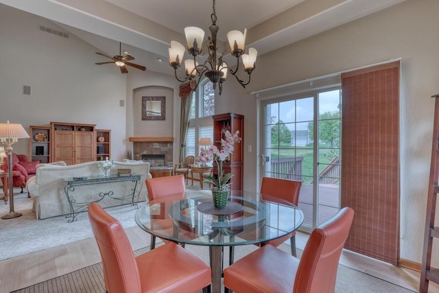 1826 Stonebridge Rd, Waukesha, WI 53188 - dining space with a stone fireplace, a ceiling fan, light wood finished floors, a chandelier, and high vaulted ceiling