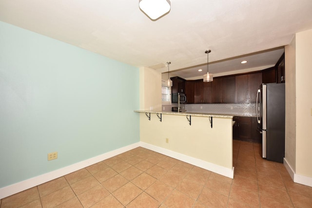 3727 E Layton Ave, Cudahy, WI 53110 - kitchen featuring appliances with stainless steel finishes, dark brown cabinets, a breakfast bar, recessed lighting, and a peninsula