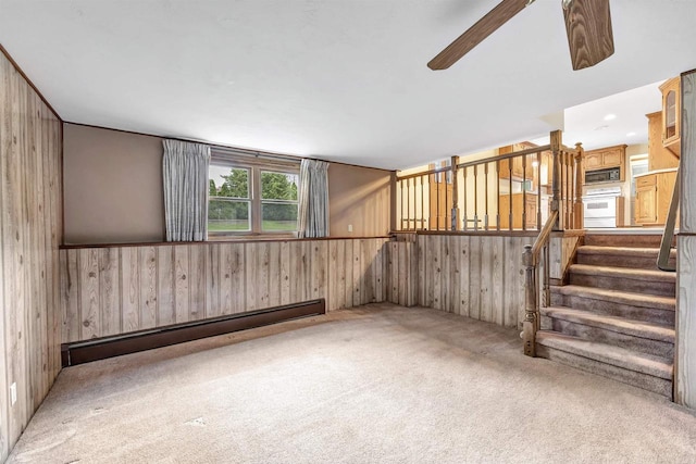 2044 E Vista Cir, De Pere, WI 54115 - empty room with a baseboard heating unit, wood walls, carpet, a ceiling fan, and stairway